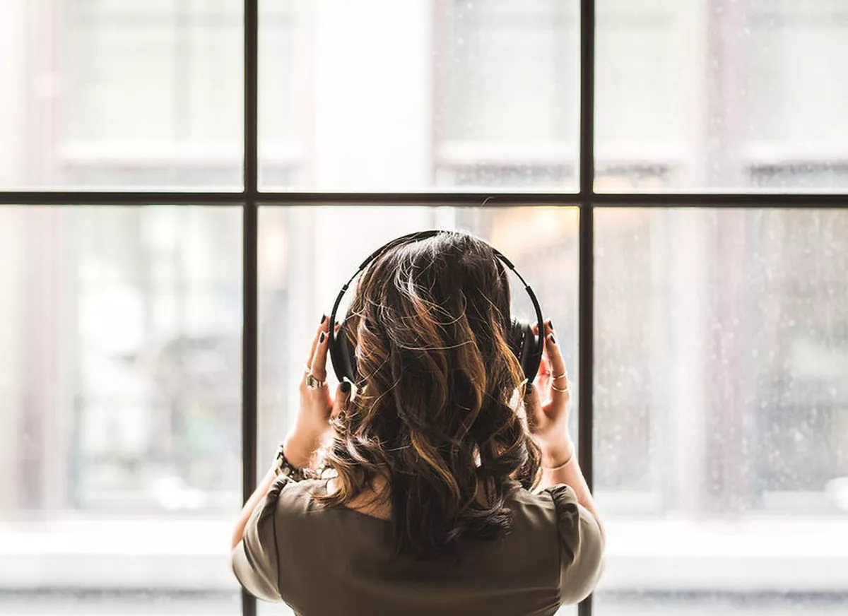 Femme écoutant les podcasts du CNES devant sa fenêtre.